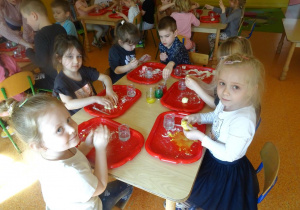 Dzieci barwią masę plastyczną na żółto przy użyciu barwników, ugniatają ciastolinę.